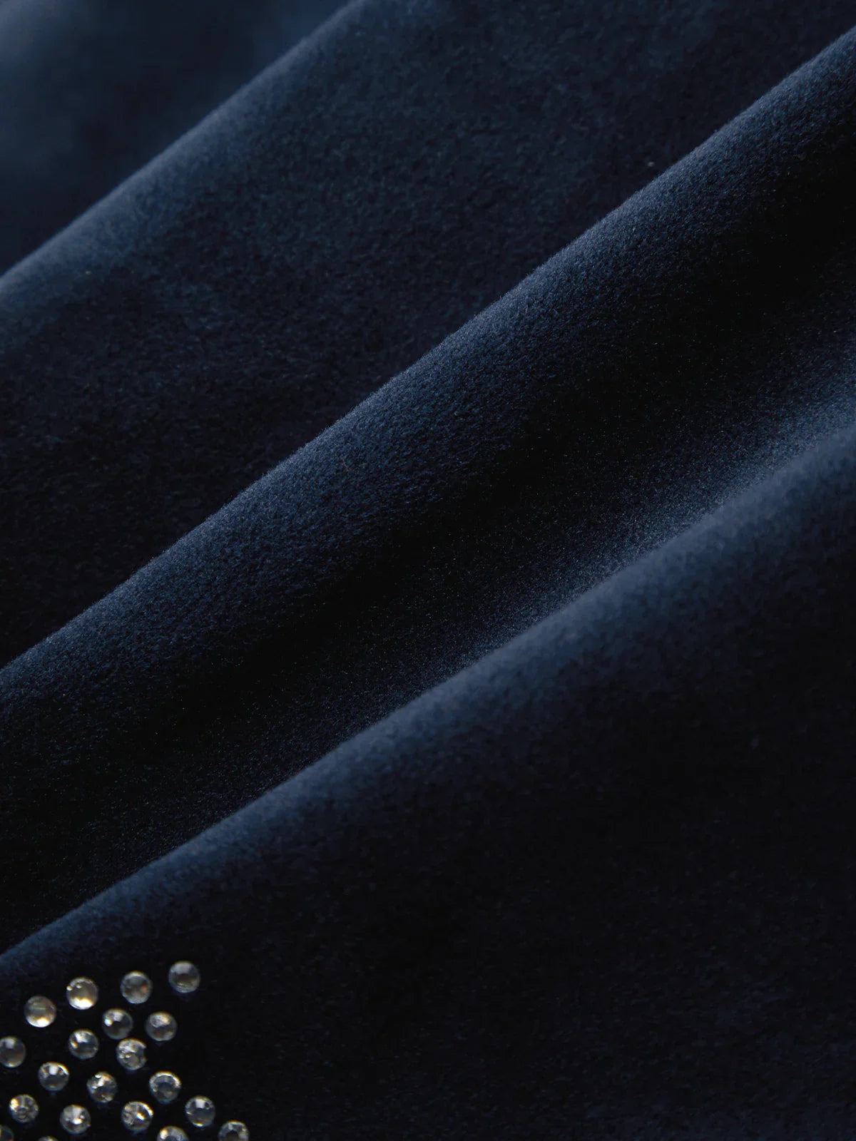 Close-up of dark blue fabric with a small embellishment of crystals.