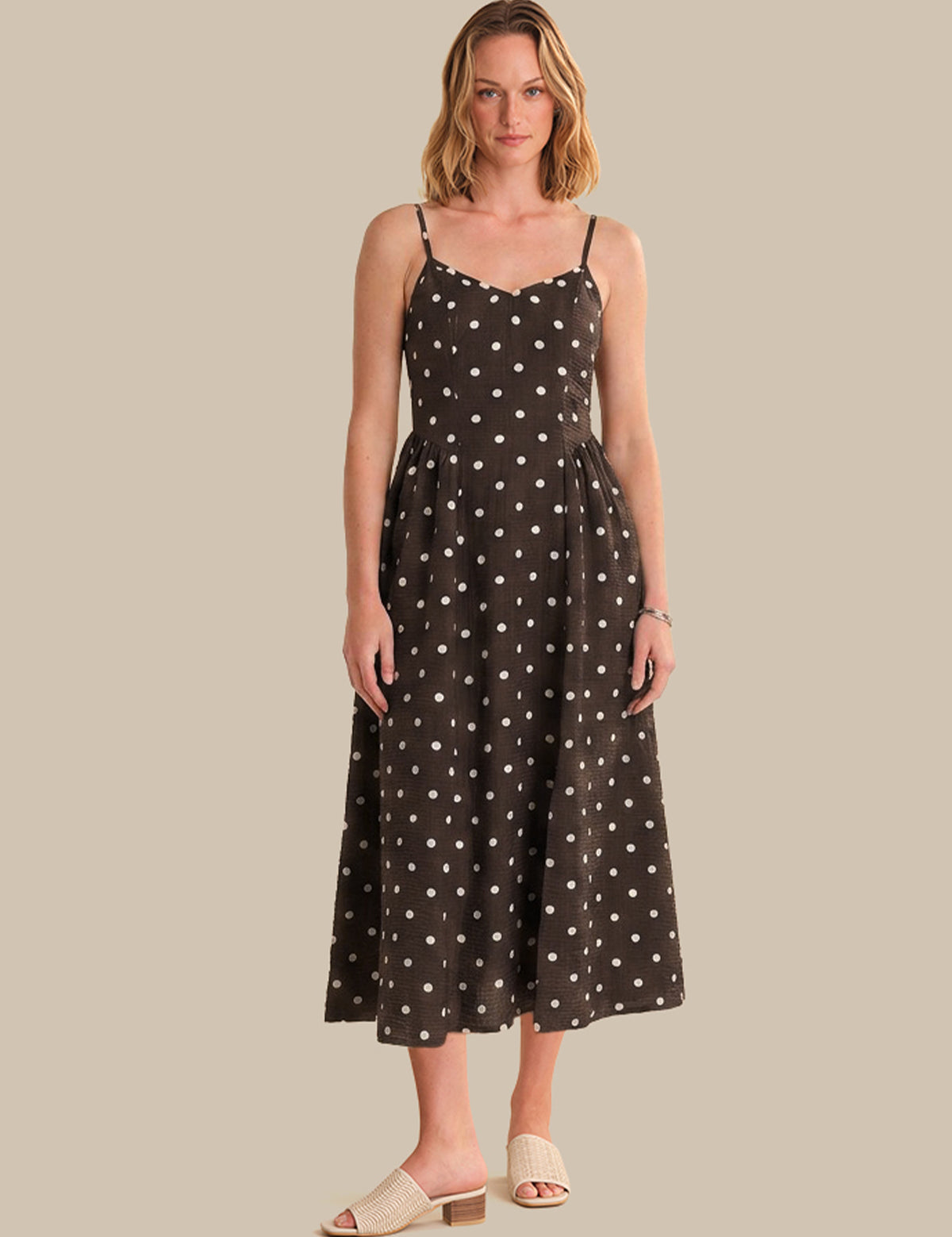 Woman wearing a black dress with white polka dots on a beige background