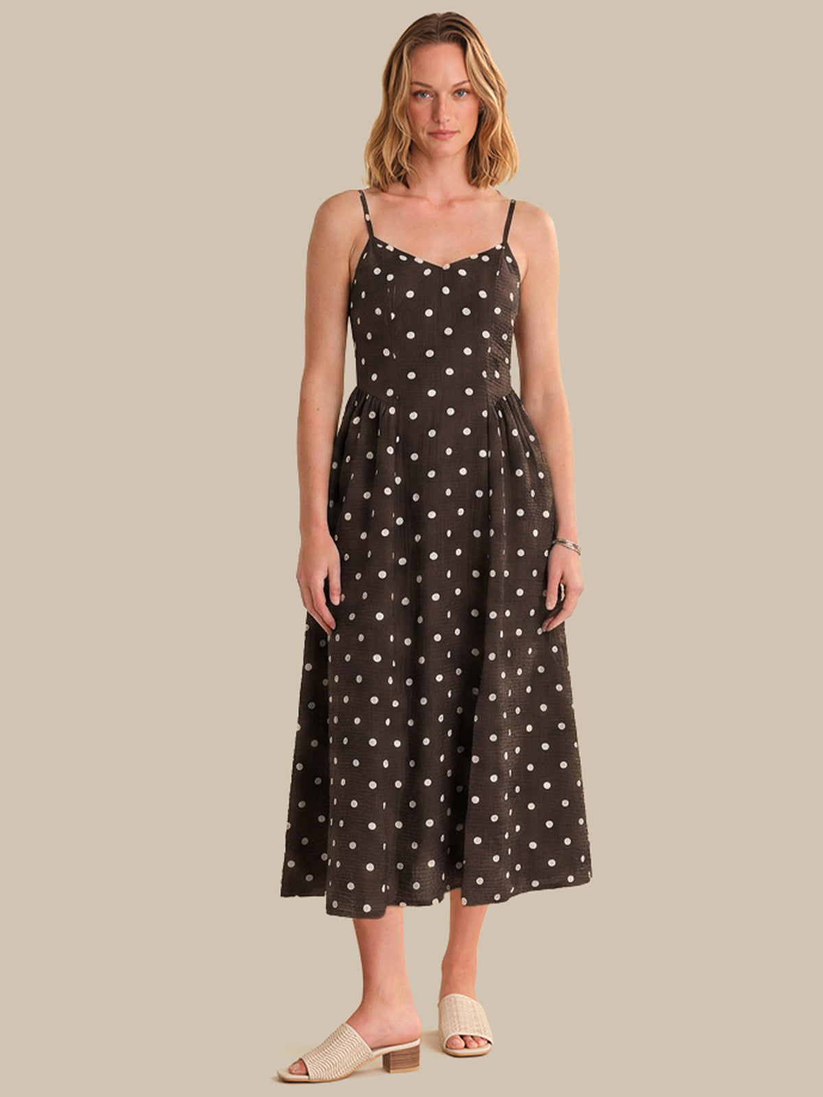Woman wearing a black dress with white polka dots on a beige background