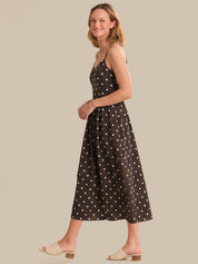 Woman wearing a black polka dot dress on a beige background