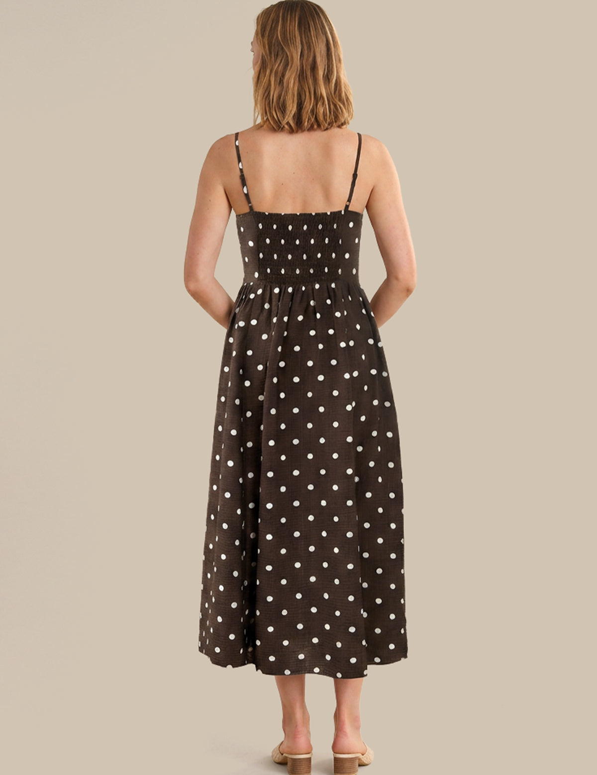 Woman wearing a black dress with white polka dots on a beige background