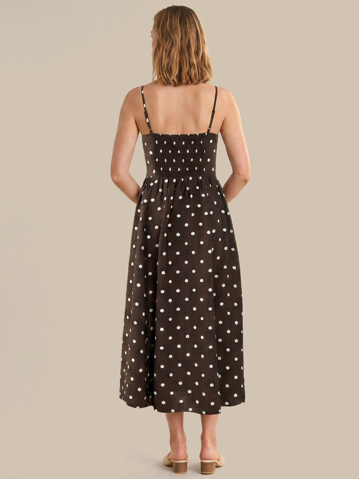Woman wearing a black dress with white polka dots on a beige background