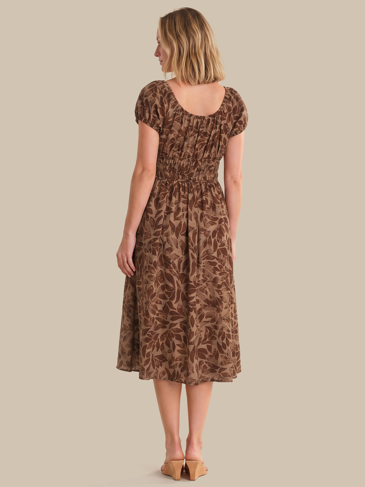 Woman wearing a brown patterned dress against a beige background