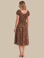 Woman wearing a brown patterned dress against a beige background