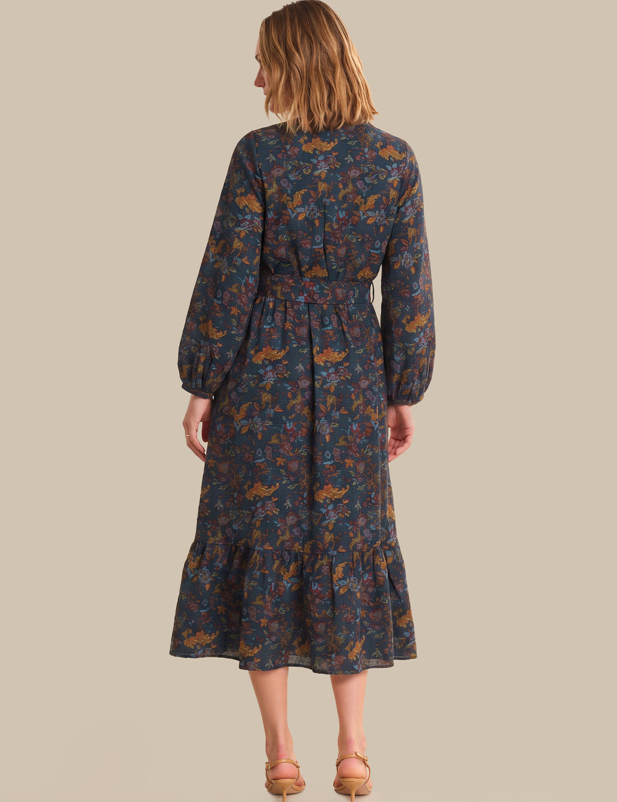 Woman wearing a long floral dress on a beige background