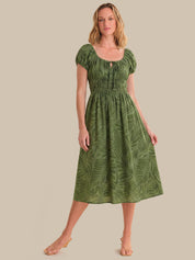 Woman wearing a green dress with leaf pattern on a beige background