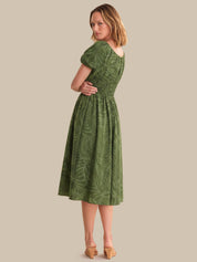 Woman wearing a green dress with a leaf pattern on a beige background