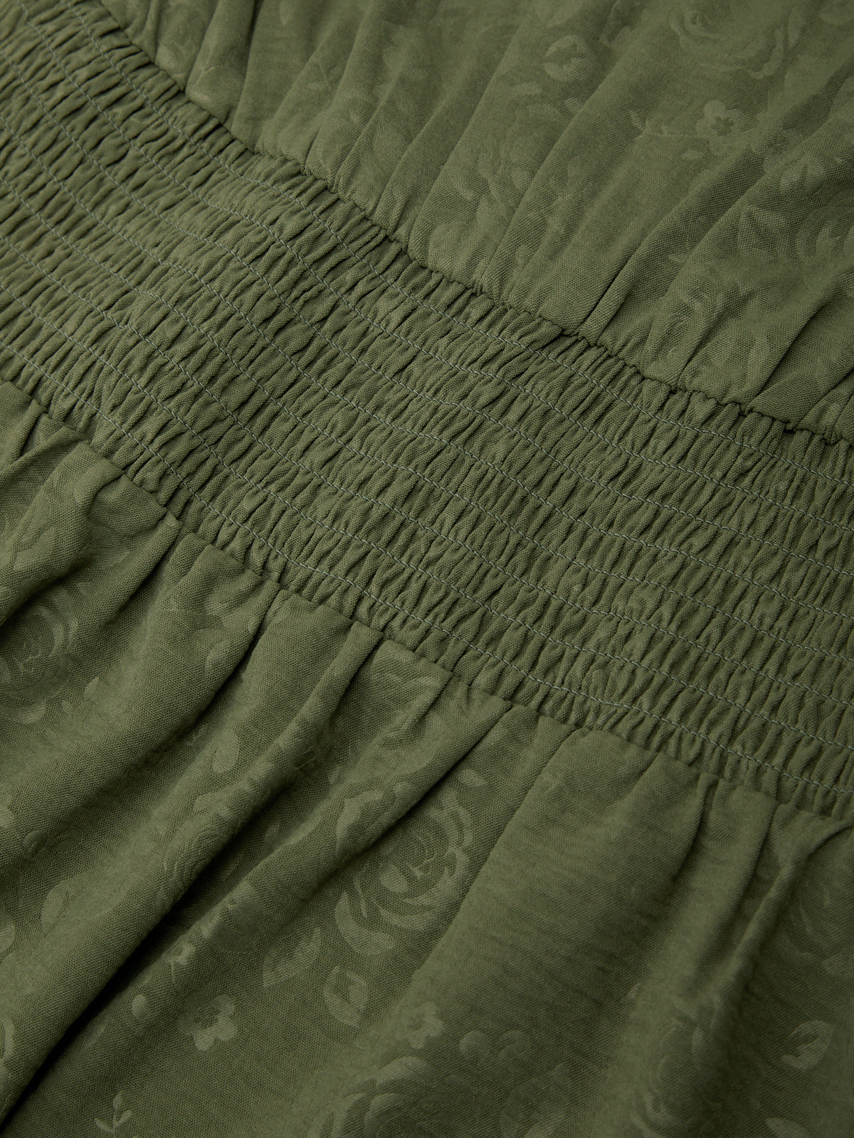 Close-up of green fabric with floral pattern and gathered waistband