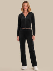 Woman wearing a black hoodie and pants on a beige background