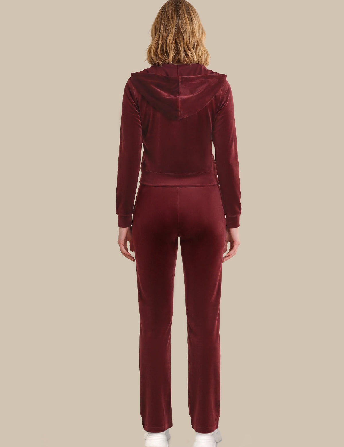 Person wearing a burgundy tracksuit on a beige background