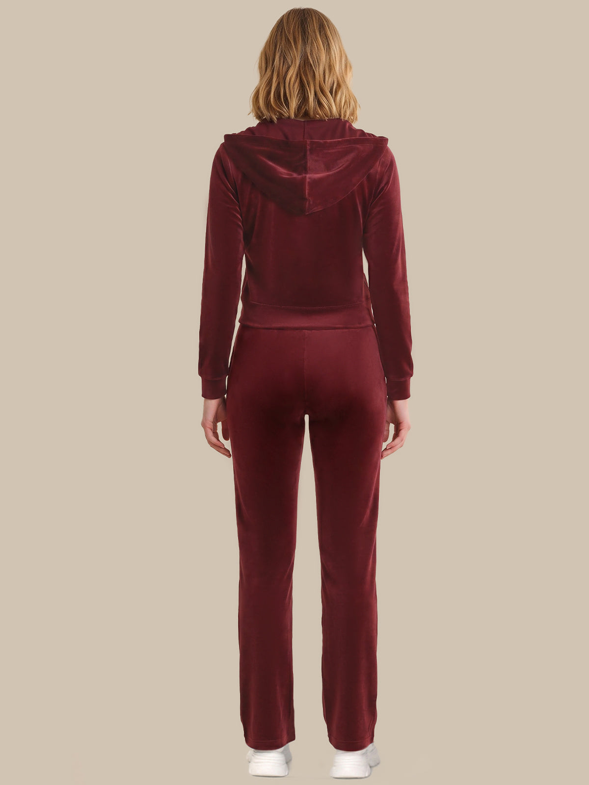 Person wearing a burgundy tracksuit on a beige background