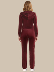 Person wearing a burgundy tracksuit on a beige background