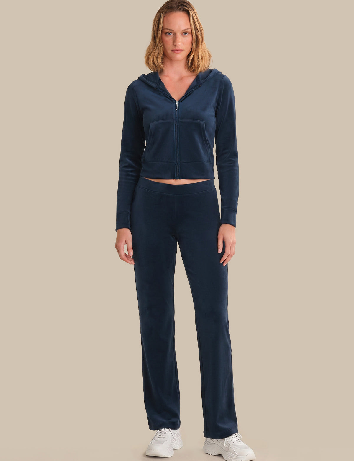 Woman wearing a navy blue tracksuit on a beige background