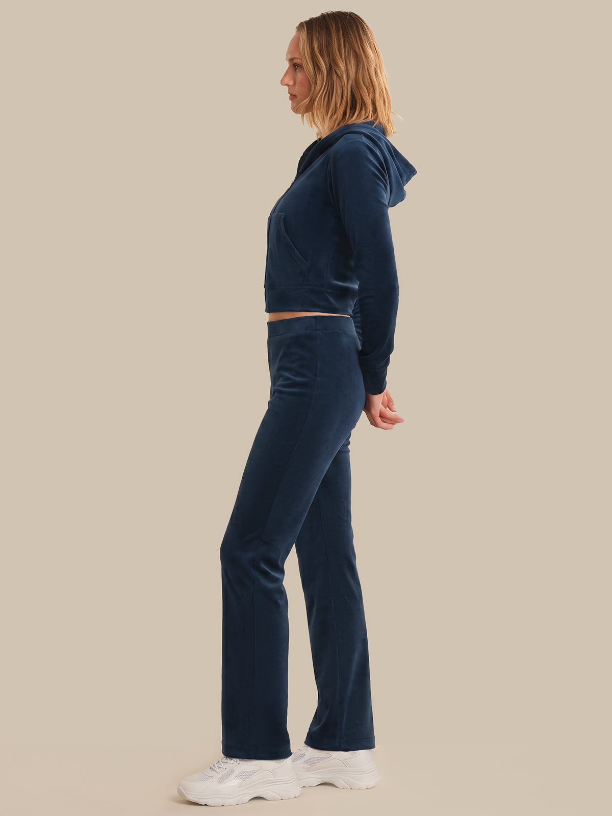Person wearing a navy blue tracksuit on a beige background