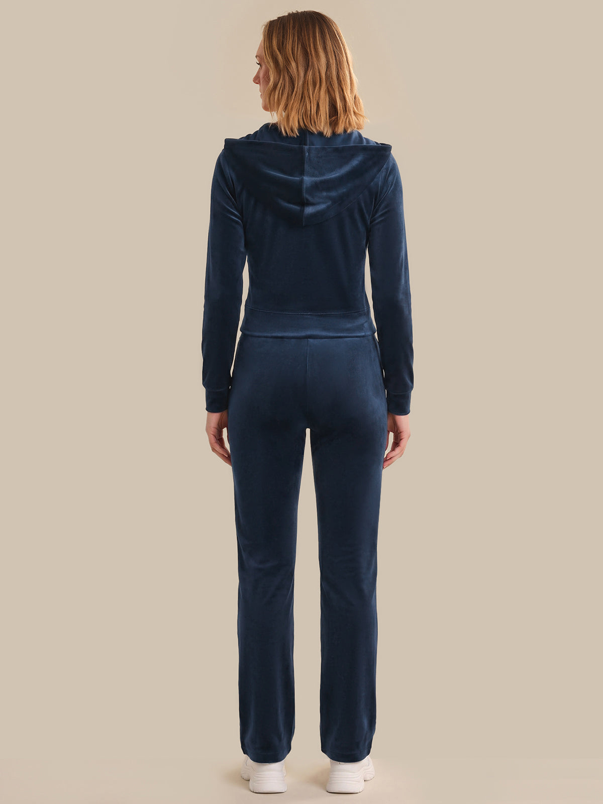 Person wearing a navy tracksuit on a beige background