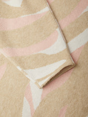 Close-up of a soft knit fabric with a wavy abstract pattern in beige, light pink, and off-white.