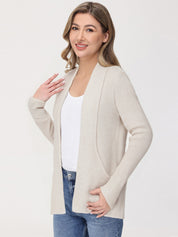 Woman wearing a beige cardigan over a white shirt and blue jeans on a white background