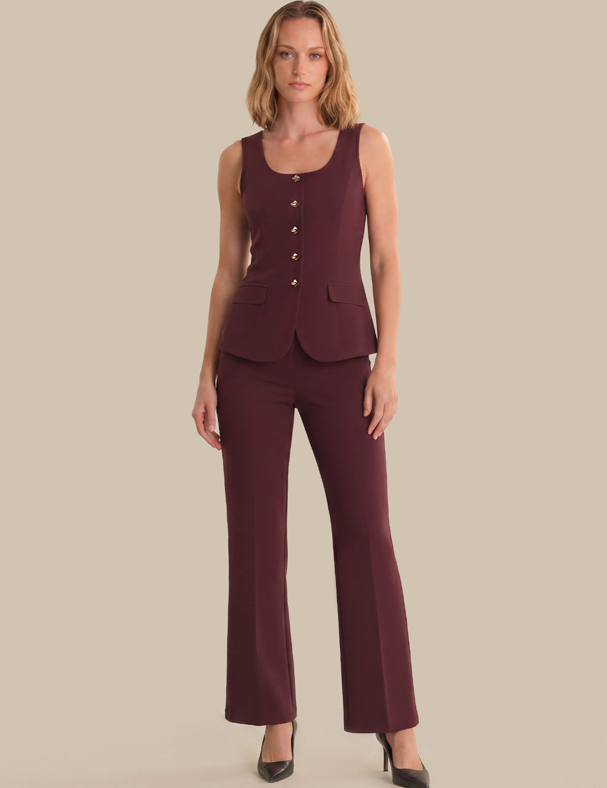 Woman wearing a burgundy sleeveless top and pants on a beige background