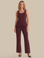 Woman wearing a burgundy sleeveless top and pants on a beige background