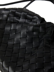 Close-up of a black woven handbag with a strap.