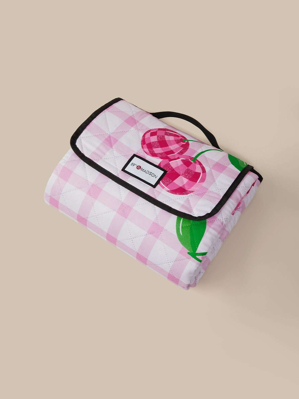 Pink checkered picnic blanket with cherry design on a beige background