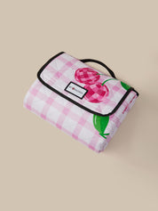 Pink checkered picnic blanket with cherry design on a beige background