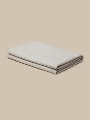 A folded light gray fabric item, likely a blanket or sheet, displayed on a solid beige background.