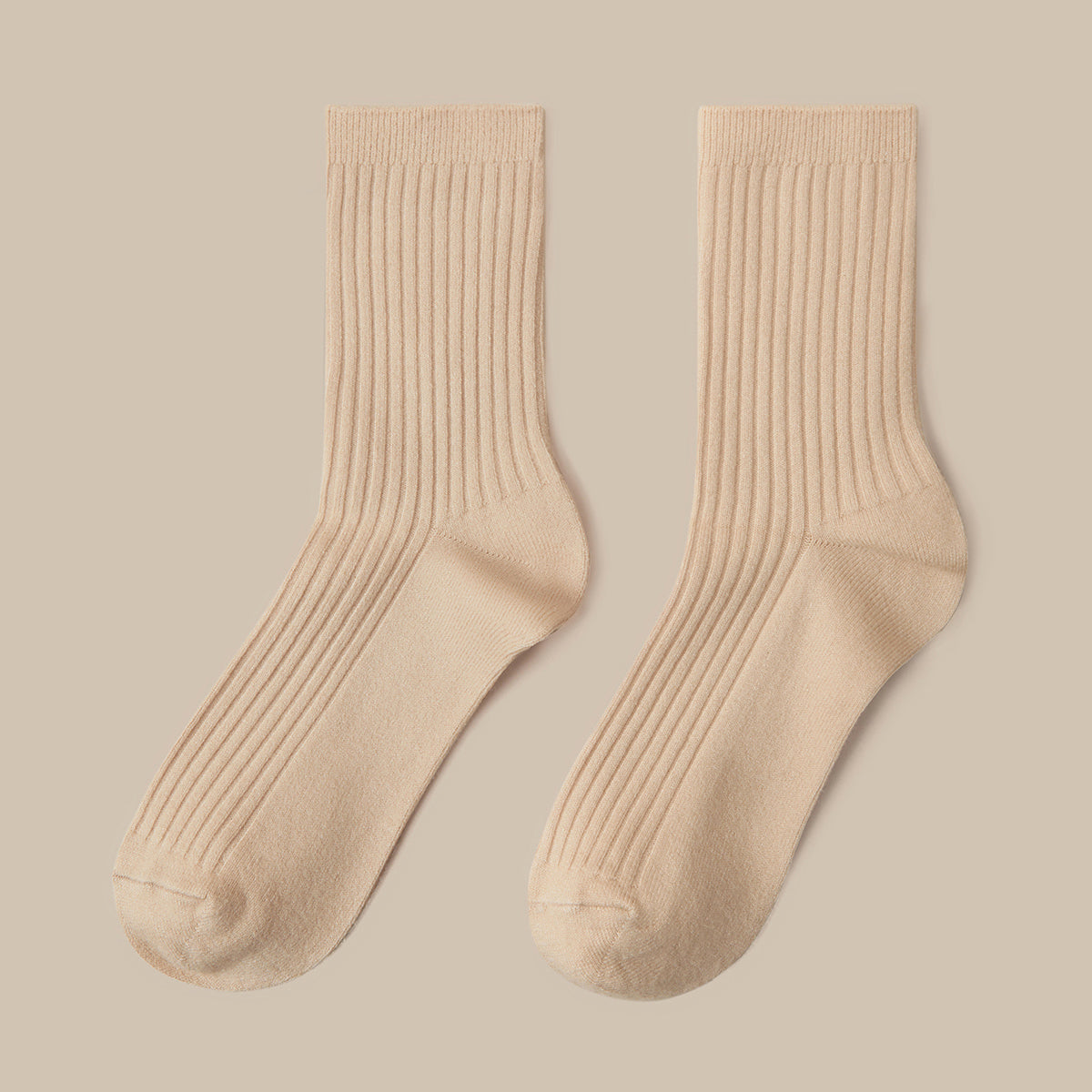 A pair of ribbed crew socks in a light beige color, displayed flat against a solid beige background.