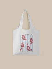 White tote bag with floral design and text on a beige background