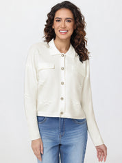 Woman wearing a white cardigan and blue jeans on a plain background