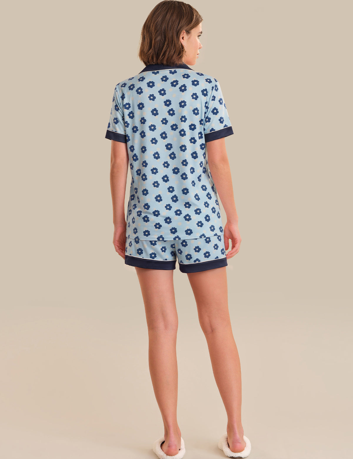 Woman wearing a blue floral pajama set on a beige background