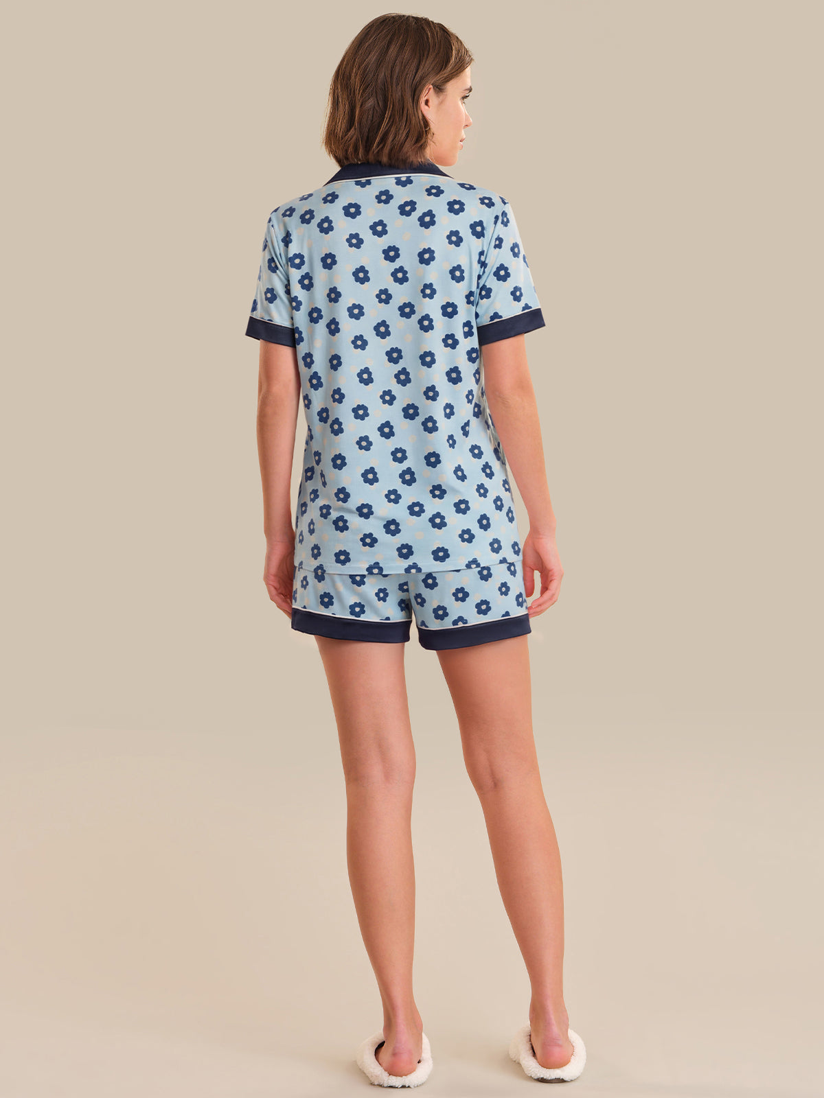 Woman wearing a blue floral pajama set on a beige background