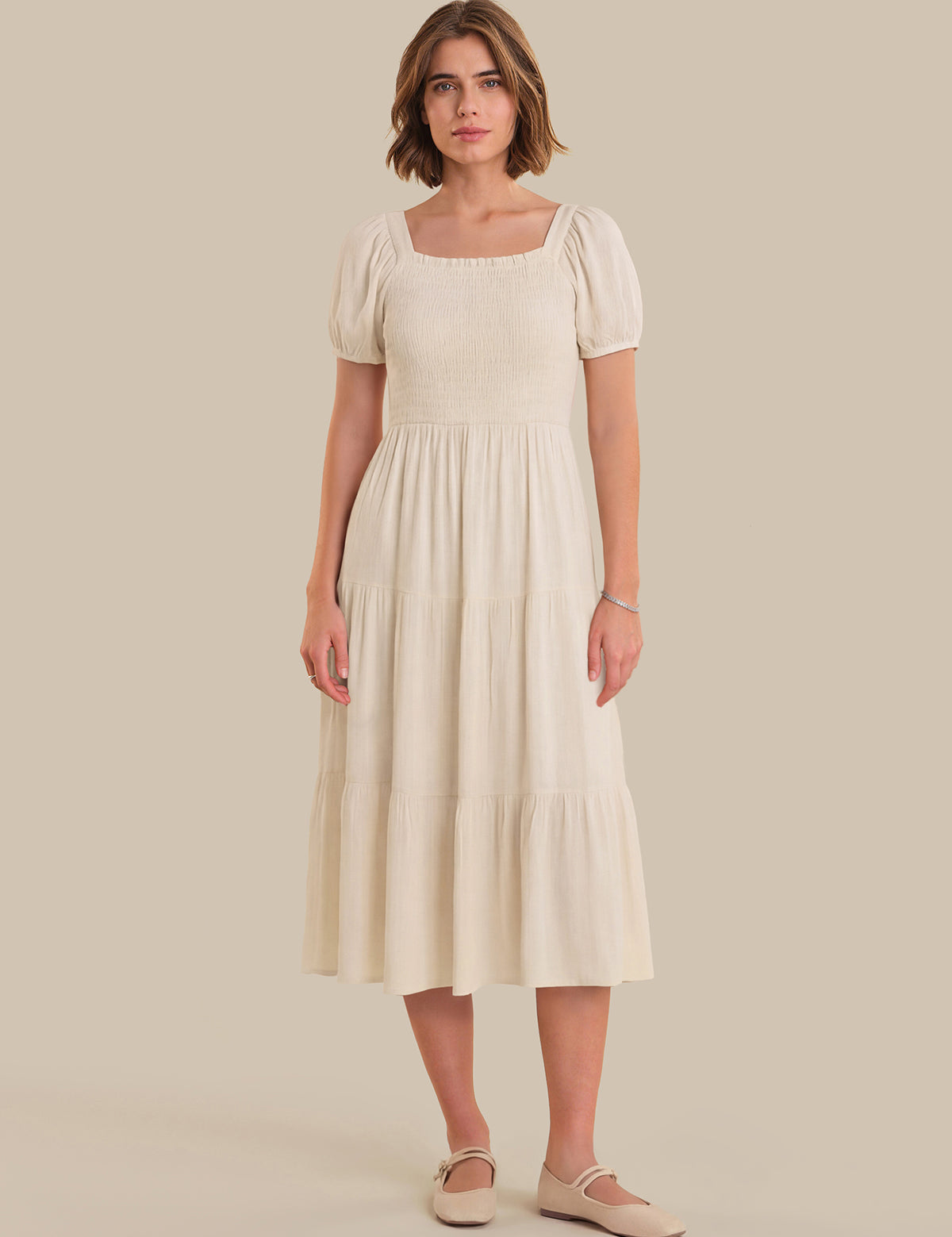 Woman wearing a beige dress against a plain background