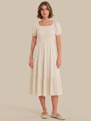 Woman wearing a beige dress against a plain background