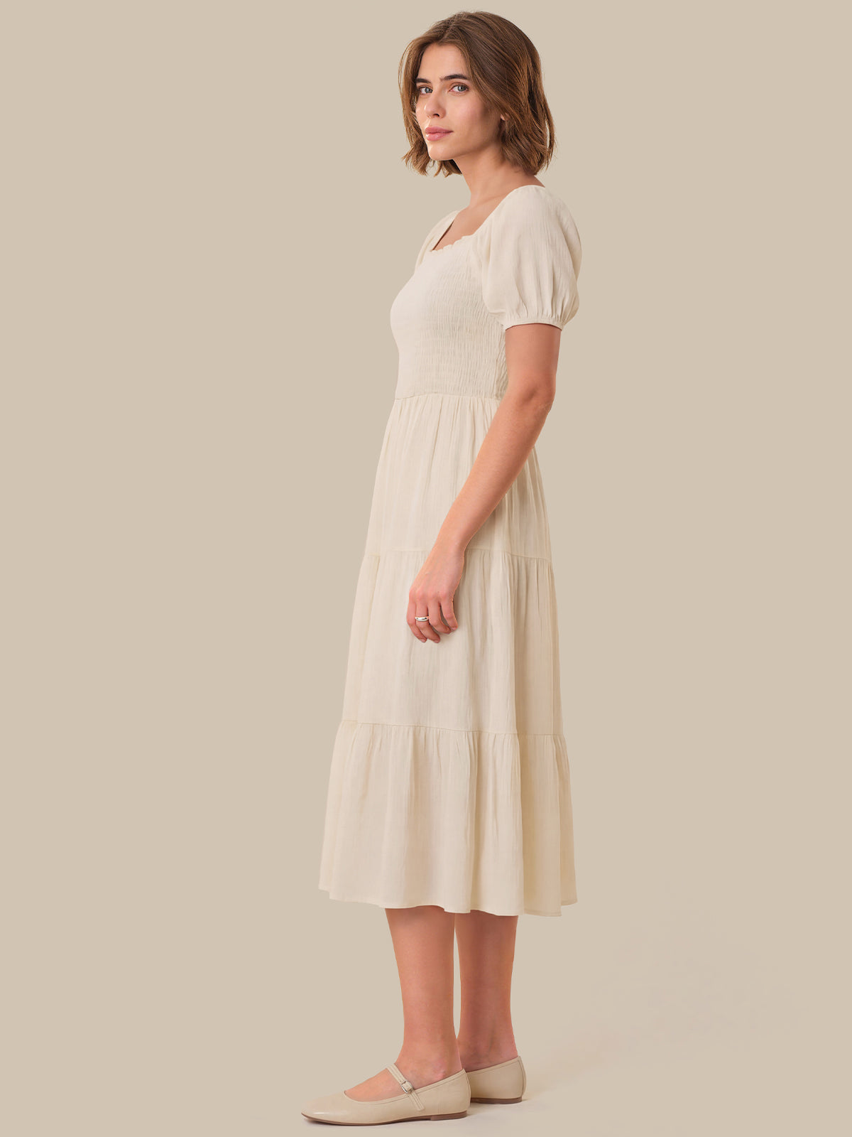 Woman wearing a white dress against a beige background