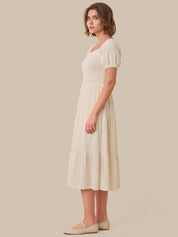 Woman wearing a white dress against a beige background