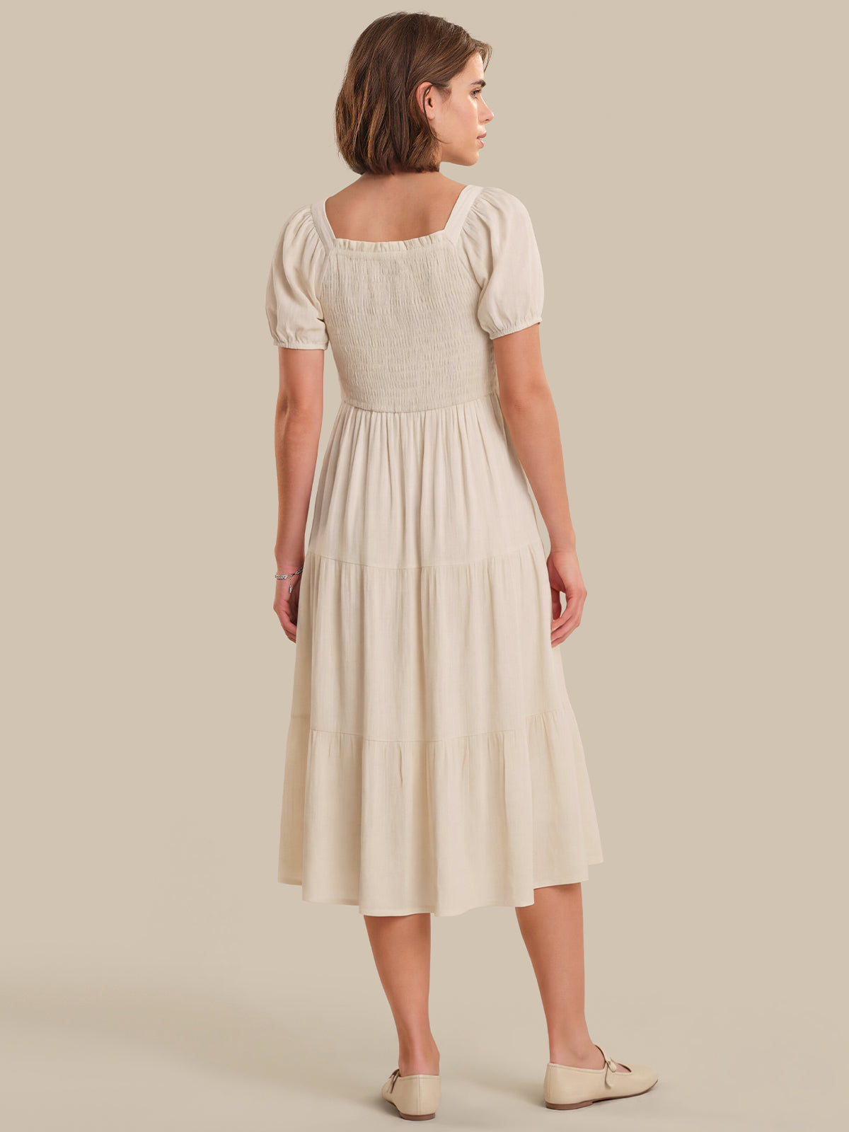 Woman wearing a beige dress against a plain background