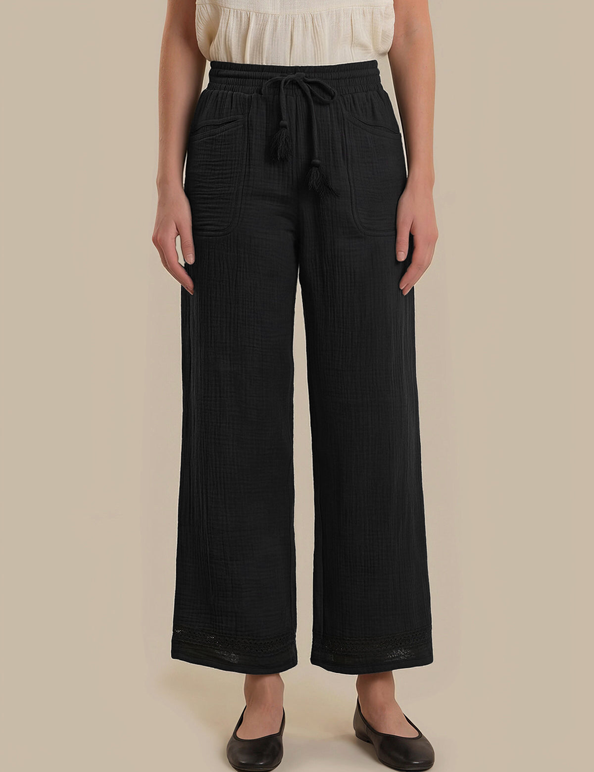 Person wearing black wide-leg pants with a beige background