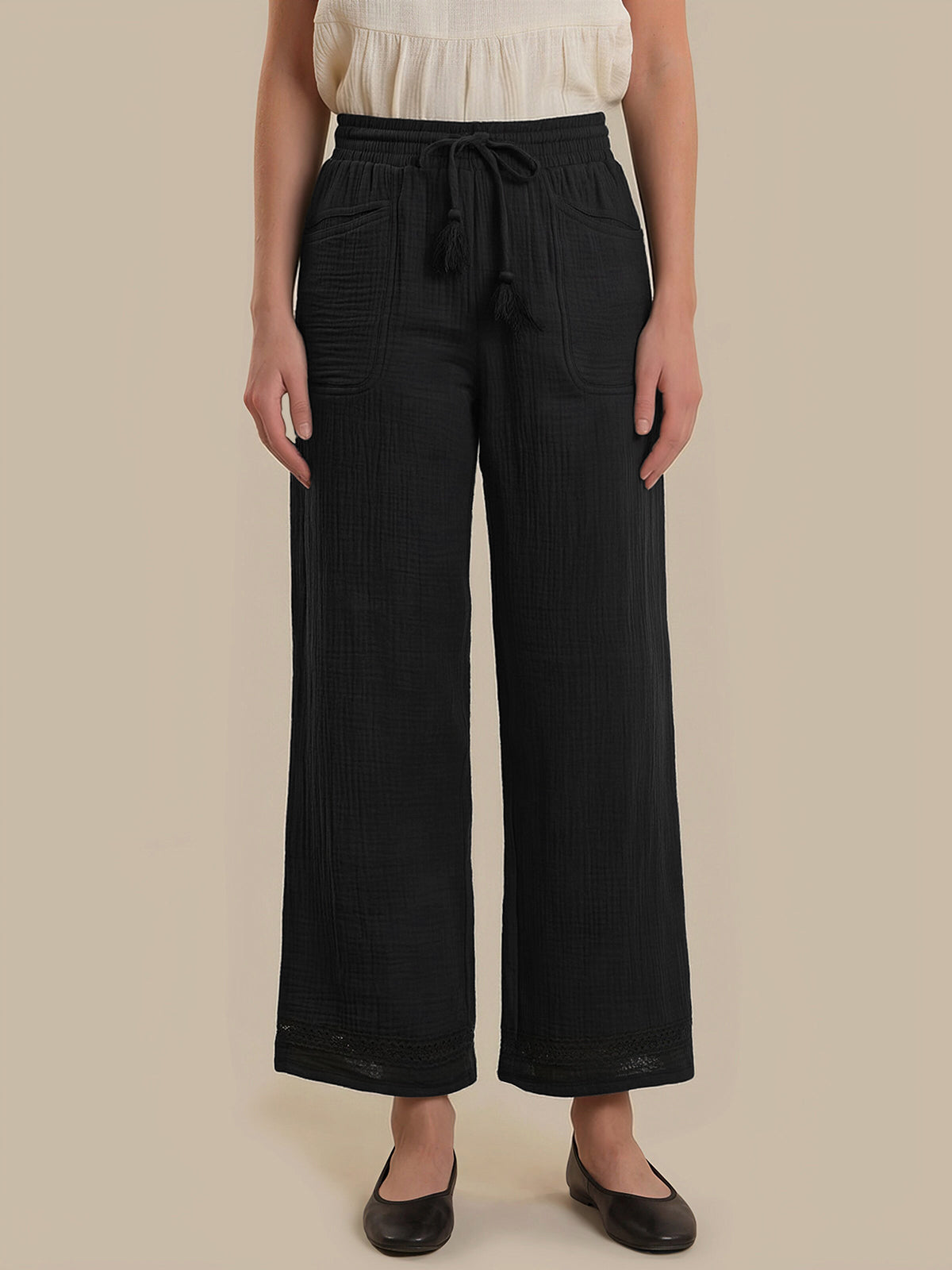 Person wearing black wide-leg pants with a beige background