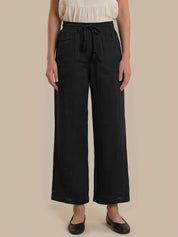 Person wearing black wide-leg pants with a beige background