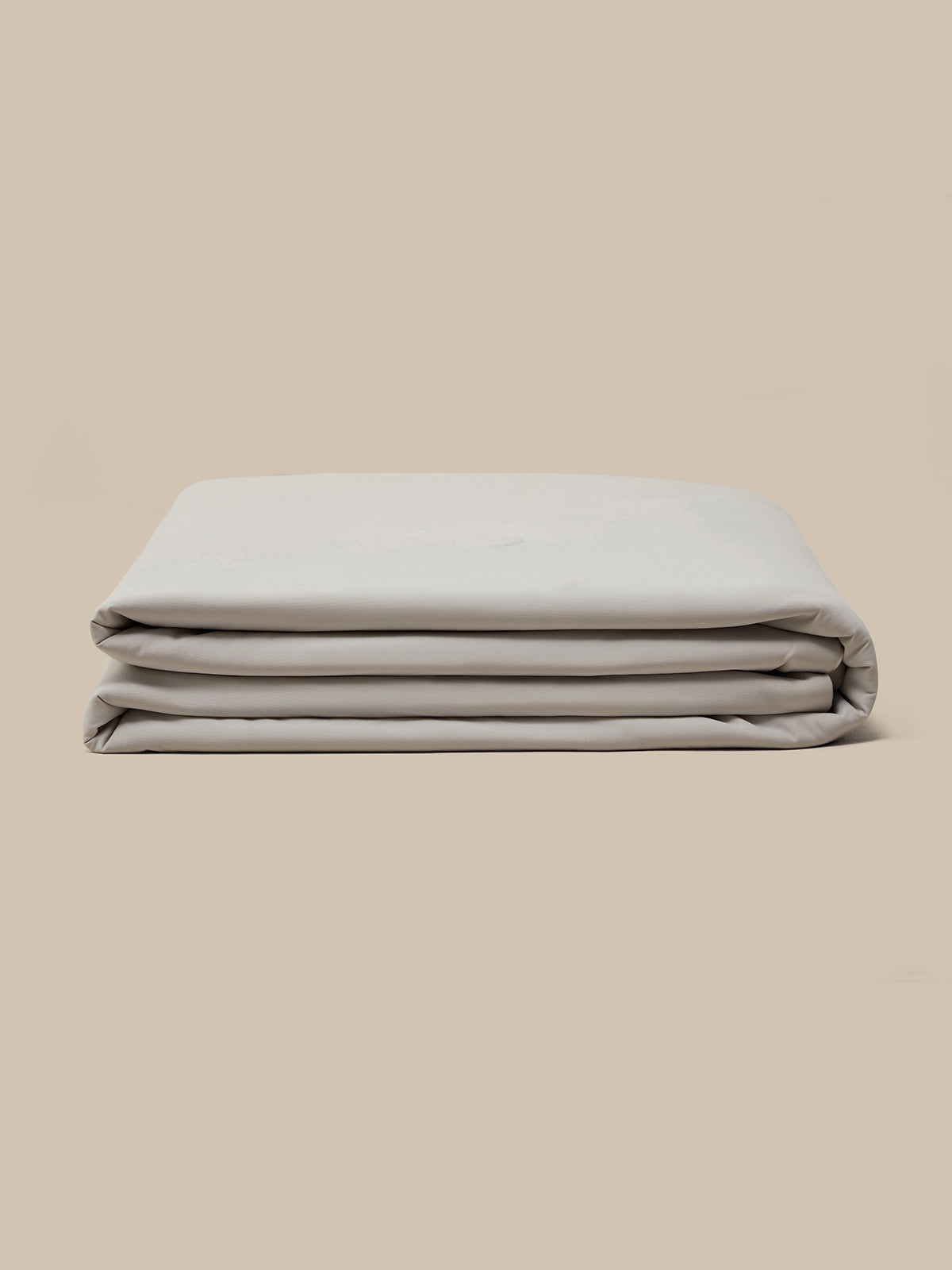 A folded quilt displayed against a plain beige background.