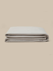 A folded quilt displayed against a plain beige background.