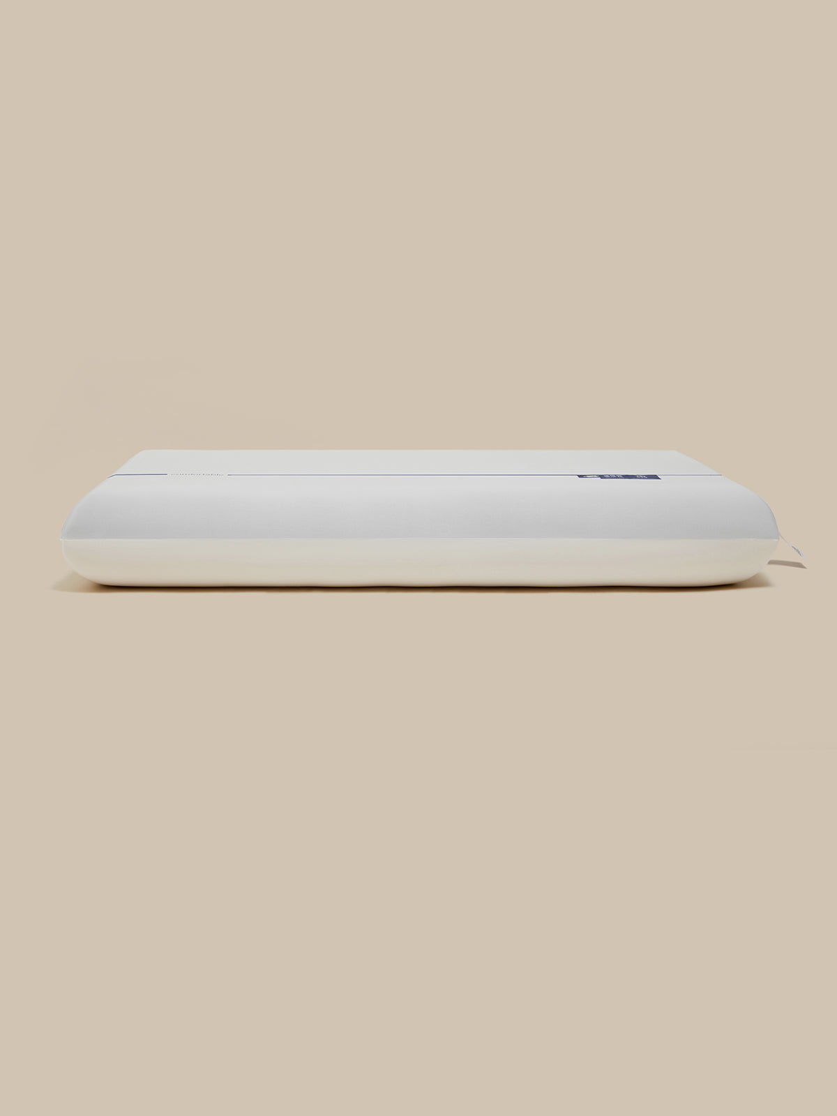 A white rectangular pillow, shown from a side profile view against a solid beige background.