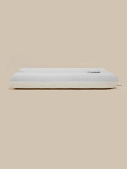 A white rectangular pillow, shown from a side profile view against a solid beige background.