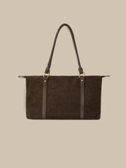 Brown leather handbag with black straps on a beige background