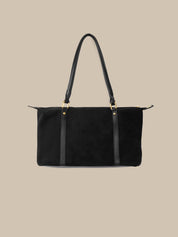 Black handbag with gold hardware on a beige background