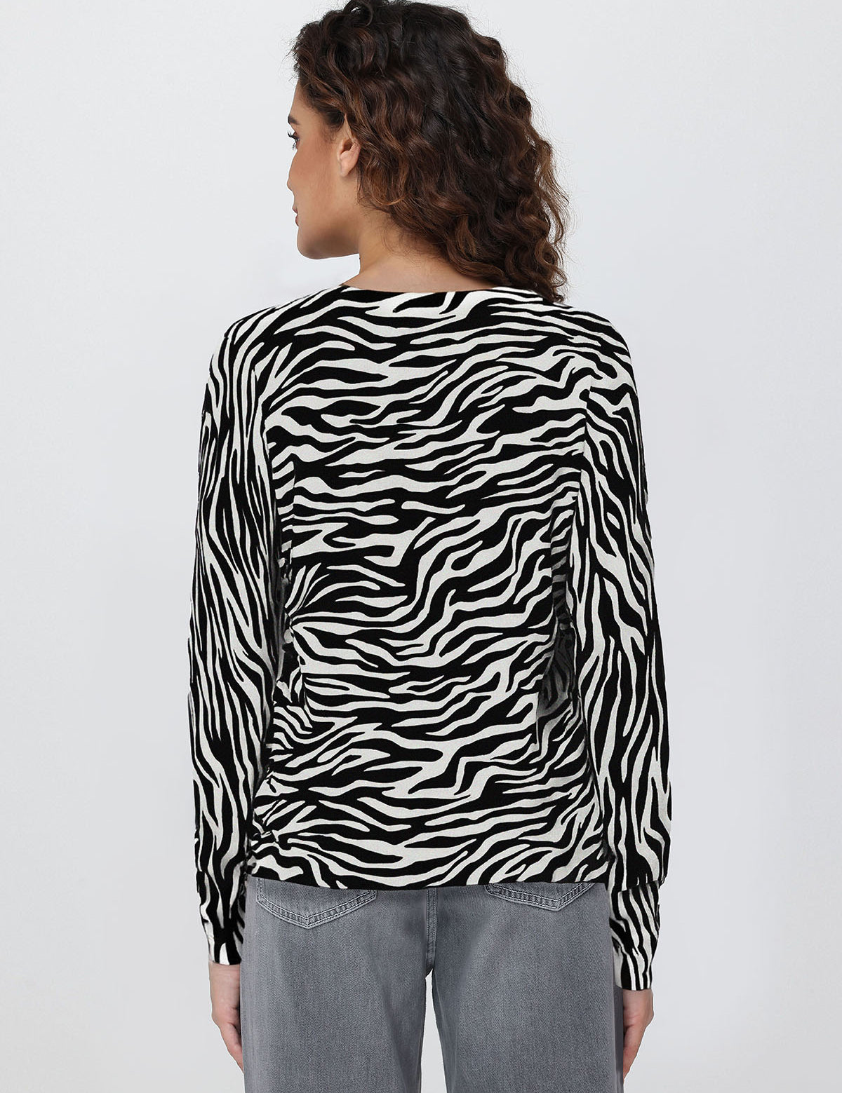 Person wearing a zebra print long-sleeve cardigan on a plain background