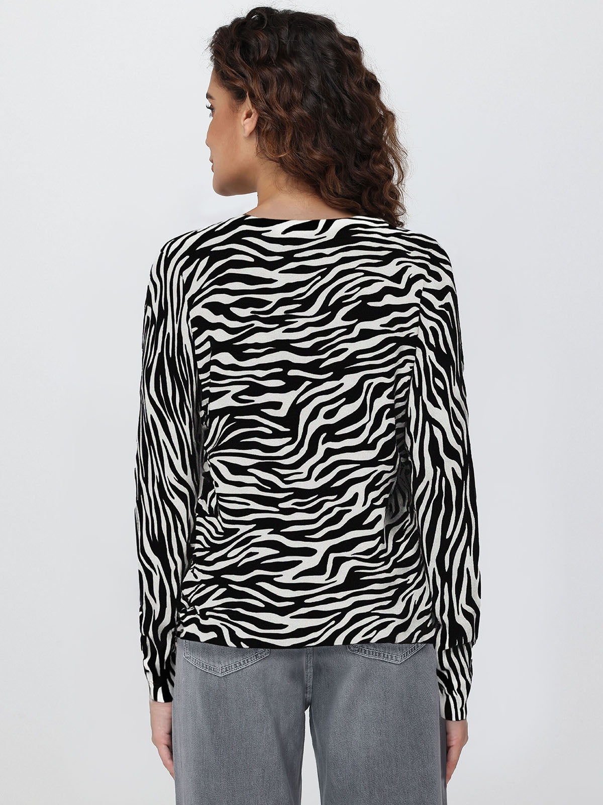 Person wearing a zebra print long-sleeve cardigan on a plain background