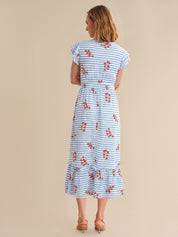 Woman wearing a blue and white striped dress with red floral patterns on a beige background