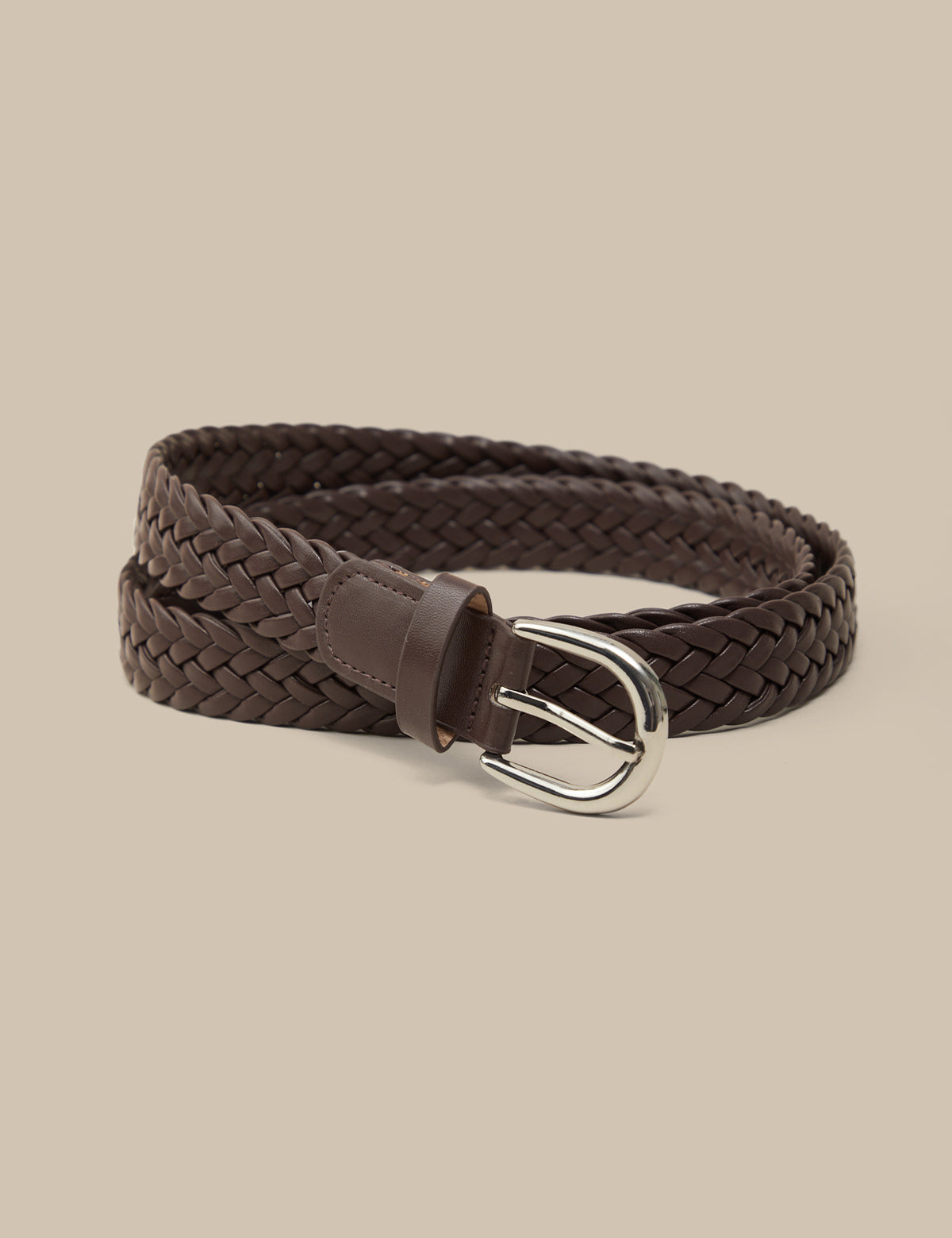 Brown braided belt with a silver buckle on a beige background